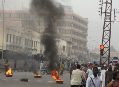 Civilians walk past burning tires lit in support of mutinying soldiers, in Bamako, Mali
