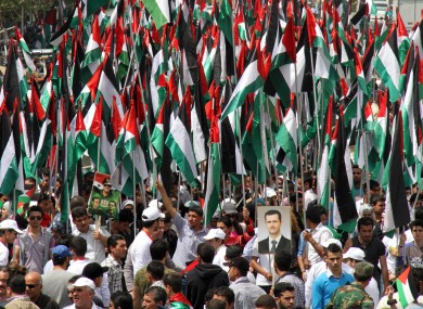 Pro-Syrian government demonstrators hold Baath party flags and a picture of President Bashar Assad at a rally at Sabe Bahrat Square in Damascus yesterday.