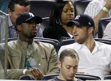 Miami Heat's Dwayne Wade, left, sits beside New York Jets quarterback Tim Tebow.