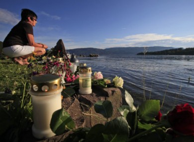 A woman looks towards Utoya and sits among floral tributes to the victims of the July 2011 attack.