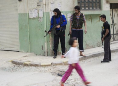 A young girl walks by rebel fighters in the Khaldiyeh neighbourhood of Homs.