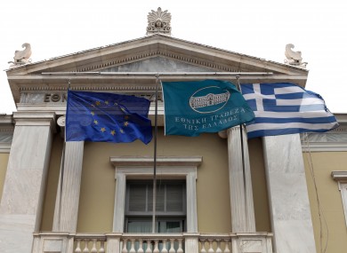 The flags of the EU and Greece fly outside the National Bank of Greece, alongside the bank's own flag, in Athens.