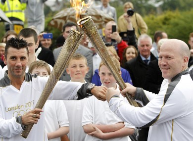 Olympic gold medallist Wayne McCullough passes the flame to Olympic silver medallist Michael Carruth at the border this morning.
