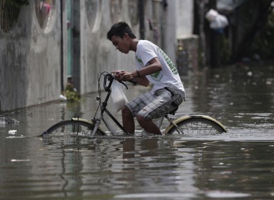 A Filipino pedals his bicycle along a flooded street in suburban Malabon, north of Manila.