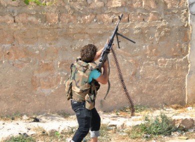 A Syrian rebel shoots towards a helicopter during clashes with government forces at Saraqeb yesterday.