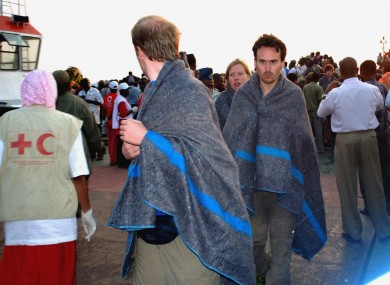 Survivors wrapped in blankets are brought ashore to Zanzibar island