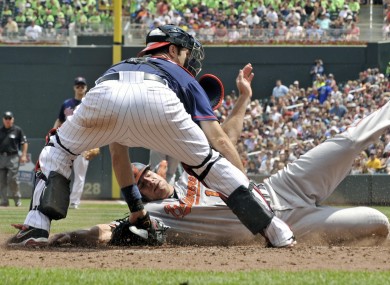 Baltimore Orioles' Chris Davis slides in to score as he beats the tag by Minnesota Twins catcher Joe Mauer in Minneapolis.
