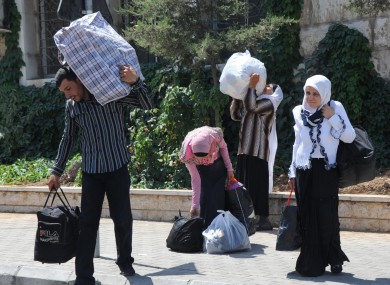 Syrians carry their belongings as they cross into Lebanon at the border crossing point in Masnaa, eastern Lebanon, about 40 kms from Damascus.