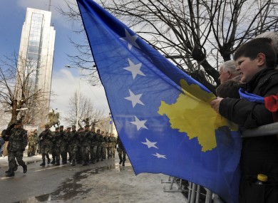 Kosovo Albanians holds Kosovo's national flag as Members of Kosovo Security Force (KSF) march during a ceremony to mark the fourth anniversary of Kosovo's independence in the main street of Kosovo capital Pristina in February 2012.