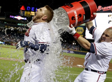 Atlanta Braves' Freddie Freeman, left, is doused with water by Eric Hinske after Freeman hit a home run in the ninth inning as the Braves beat the Marlins 4-3 to clinch at least an NL wild-card playoff berth last night.