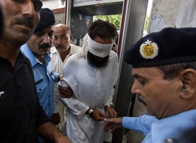 Pakistani police officers escort blindfolded Muslim cleric Khalid Chishti to appear in court in Islamabad, Pakistan, Sunday, Sept. 2