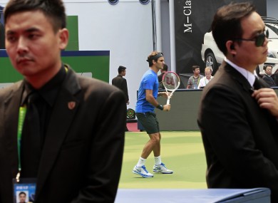 Roger Federer practices as he is guarded by body guards yesterday.