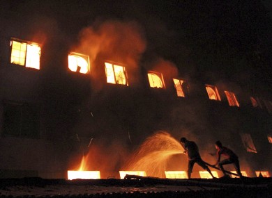 Bangladeshis and firefighters battle a fire at a garment factory in the Savar neighborhood in Dhaka, which killed at least 112 people.