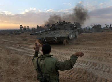 An Israeli soldier guides a tank to a new position at a staging area near the Israel Gaza Strip Border, southern Israel yesterday.
