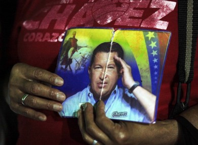 A person holds up images of Venezuela's President Hugo, right, and Venezuela's independence hero Simon Bolivar as people gather to pray for Chavez at Simon Bolivar square in Caracas, Venezuela,