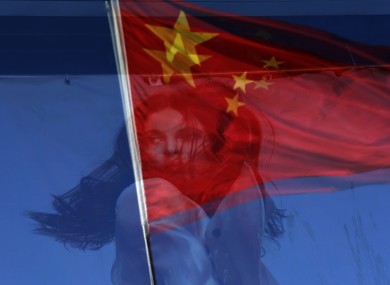 A Chinese national flag is reflected on a fashion poster at a shopping mall in Beijing, China