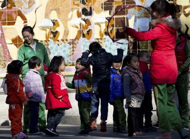 Kindergarten teachers play with children during an outdoor activity at the Ritan Park in Beijing.