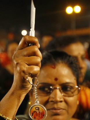 A woman poses for photographs with a knife she received during a distribution by local leaders of Shiv Sena, a right-wing party in Mumbai, India.