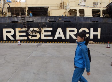 A woman walks by Nisshin Maru, Japan's whaling ship, moored at a port in Tokyo