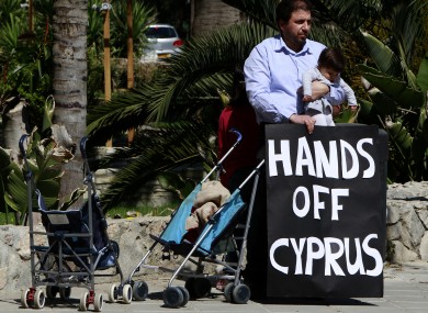 A protestor with his child hold a banner outside of parliament during a crucial meeting in capital Nicosia, Cyprus, yesterday.