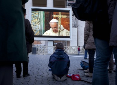 People watch Pope Francis on a giant screen in St. Peter's square as he celebrates his inaugural Mass with cardinals inside the Sistine Chapel, at the Vatican