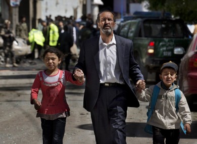 An Afghan man directs his children away from the scene where a suicide car bomber attacked a NATO convoy in Kabul, Afghanistan.