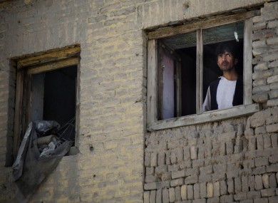 File: An Afghan man peers through a destroyed window of his house at the scene where a suicide car bomber attacked a NATO convoy in Kabul last week
