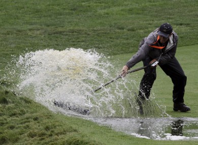 A course worker clears water from the 16th fairway