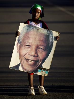 Lehlogonolo Nkosi, 7, holds a portrait of Nelson Mandela as she and her grandmother Florah, 52, unseen, leave after visiting the entrance where flowers and get-well messages have been left by well-wishers at the Mediclinic Heart Hospital.