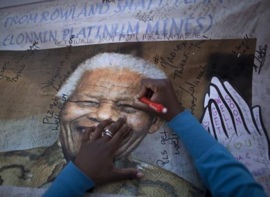 A South African woman, writes a get well message at a banner showing former South African President Nelson Mandela, placed at the entrance to the Mediclinic Heart Hospital.
