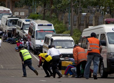 Paramedics take cover beside parked ambulances outside the Westgate mall