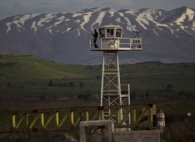 A U.N. peacekeeper from the UNDOF force stands guard on a watch tower at the Quneitra Crossing in the Golan Heights