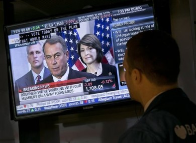 Specialist Frank Masiello watches a television monitor on the floor of the New York Stock Exchange showing a Washington news conference by House Speaker John Boehner