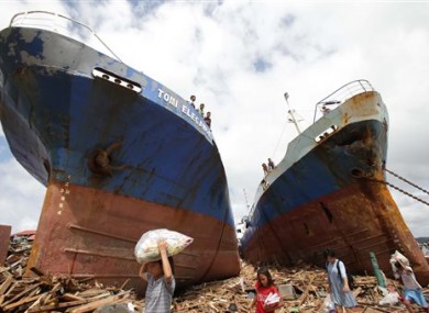 Survivors pass by two large boats after they were washed ashore by strong waves caused by Typhoon Haiyan in Tacloban city, Leyte province central Philippines