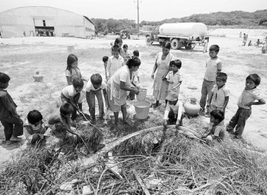 Guatemalan refugees fill water containers with rainwater at a camp in China, Mexico, July 9, 1984 - they had fled the strife which separated families like the Velasquez siblings.