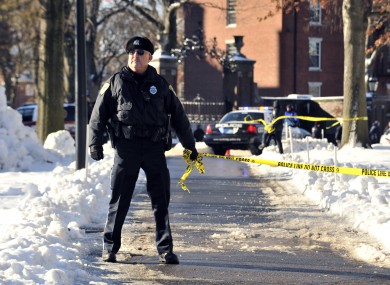 A police officer holds tape to keep people out from part of Harvard University today.