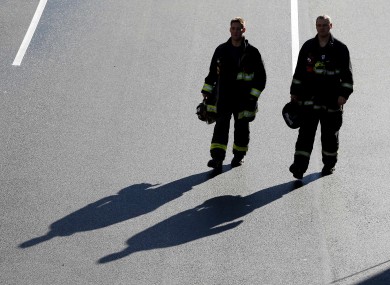 A pair of firefighters arrive at the finish line of the Boston Marathon.