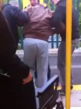 Man being helped off the train as passengers help with his wheelchair.