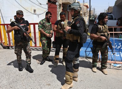 A member of Iraq's Special Weapons and Tactics Team (SWAT), center, stands with other Iraqi Shiite gunmen from al-Mahdi army, at a street linked to a Shiite mosque, in the northern oil rich province of Kirkuk.