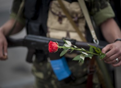 A pro-Russian fighter holds a gun and a rose after taking the oath of allegiance to the self-proclaimed Donetsk People's Republic
