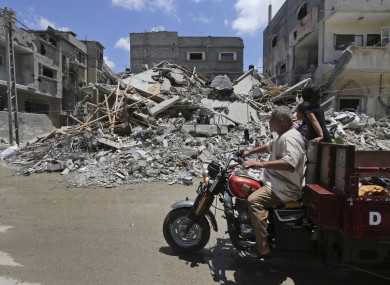 Palestinians drive by the rubble of a house destroyed by an overnight Israeli missile strike during the week-long conflict in Rafah, southern Gaza Strip.