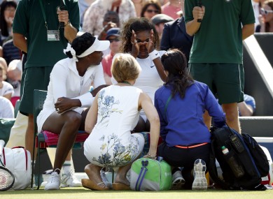 Serena (right) receives treatment alongside sister Venus Williams before their doubles match.