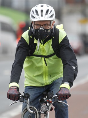 A cyclist wearing a mask cycles across London Bridge.