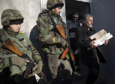 Ukrainian army soldiers guard a district election commission as an election official carries ballots to a polling station.