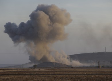 A huge plume of smoke rises after an airstrike in eastern Kobani, Syria, behind a hilltop where militants with the Islamic State group had raised their flag