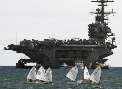 Sail boats pictured beside the American aircraft carrier USS George HW Bush outside Piraeus port in Greece.