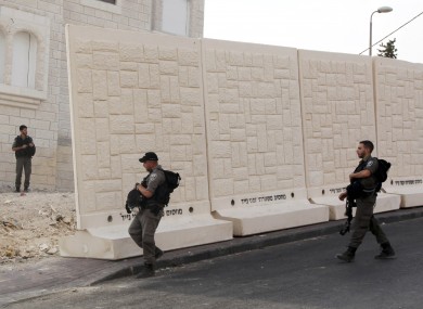 Israeli border policemen walk by the wall being built between Palestinian and Jewish neighbourhoods in Jerusalem.
