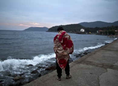An Afghan refugee walks by the sea on the island of Lesbos, Greece, after arriving from Turkey yesterday