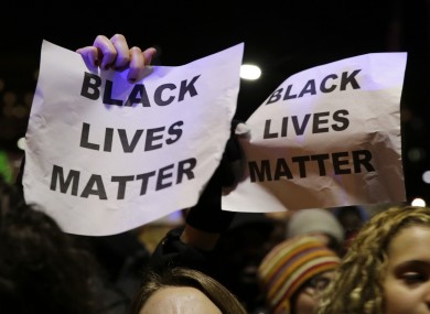 Protesters hold up signs during a demonstration against the deaths of two unarmed black men at the hands of white police officers in New York City and Ferguson.