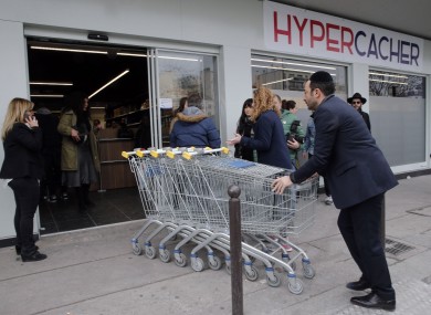 A worker pushes trolleys into the Hyper Cacher, the scene of a deadly attack in January 2015, during its reopening.